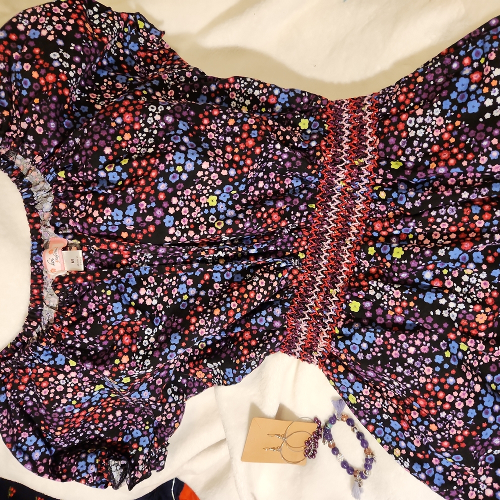 Black velvety top with multi-colored flowers, short sleeve and cinched waist.
